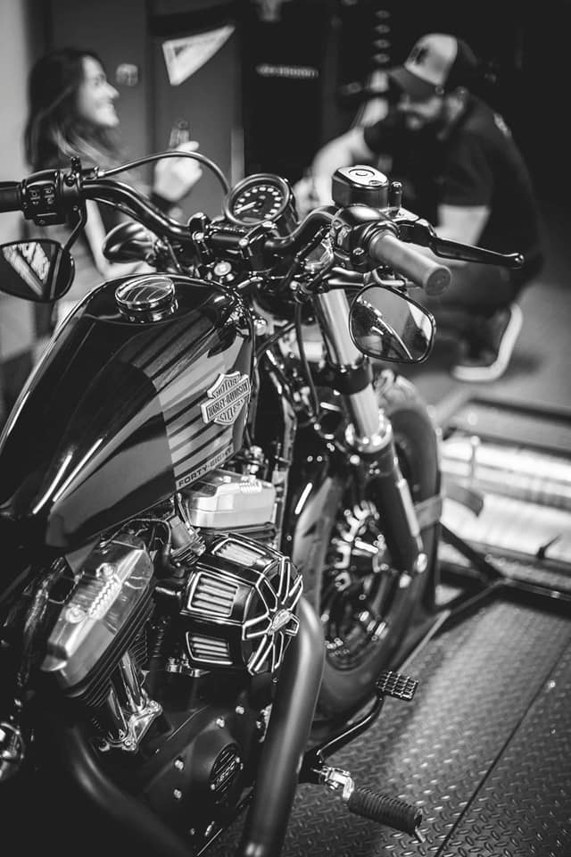 Moto Harley Davidson noire avec deux personnes en arrière-plan dans un magasin.