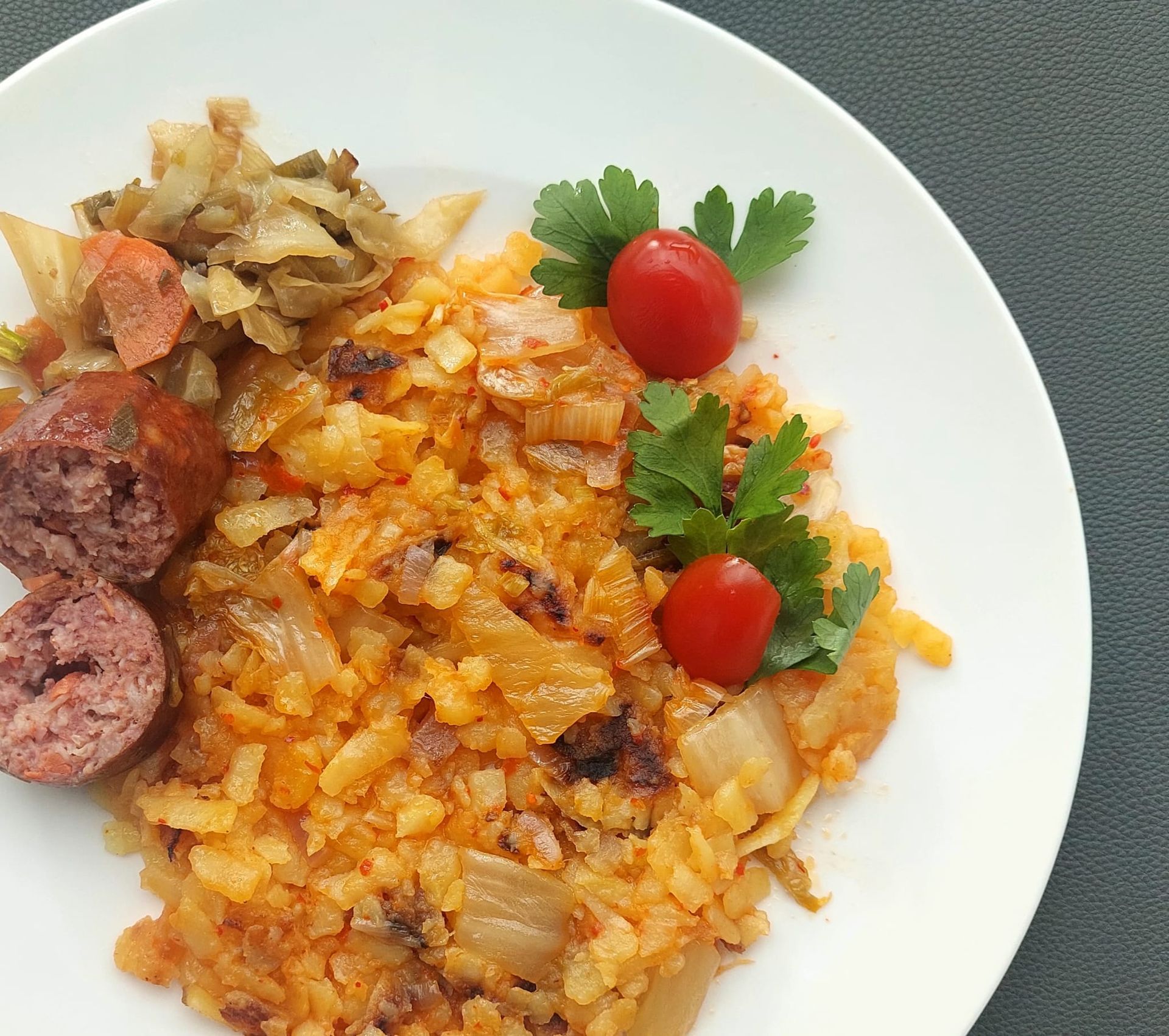 Une assiette blanche garnie de saucisses de riz et de tomates