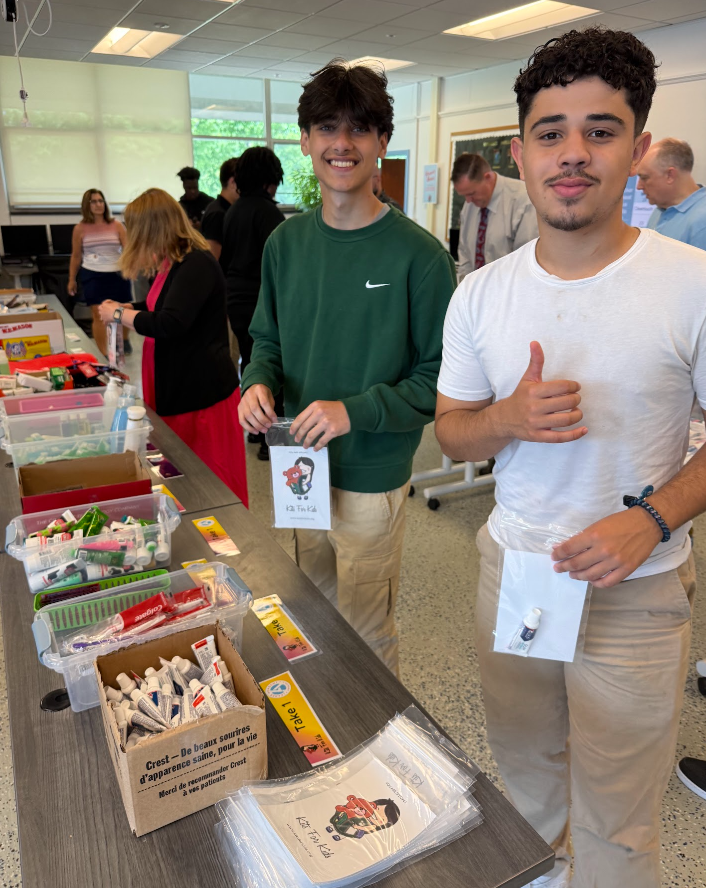 Two people at a dessert table, one giving a thumbs up in a bright indoor room