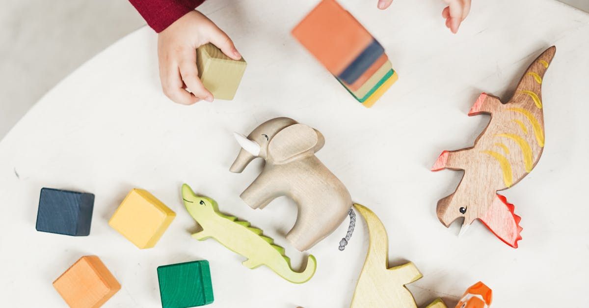 Hands arranging colorful wooden puzzle pieces on a white surface
