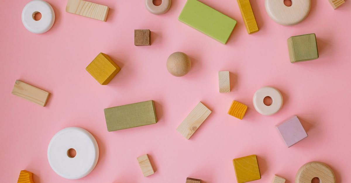 Assorted pastel wooden blocks and shapes scattered on a pink background