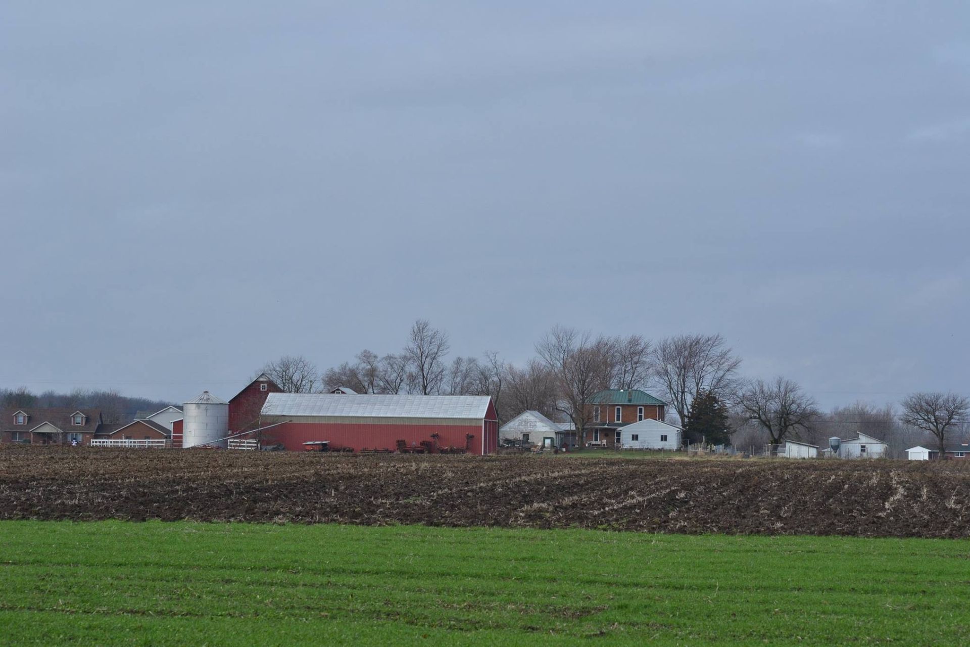 A farm with a red barn and a green field in the foreground