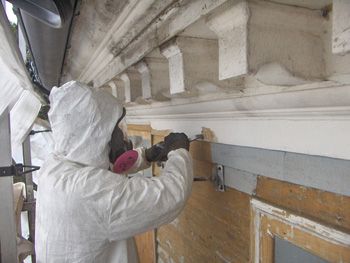 A man in a protective suit is working on Lead Paint removal.