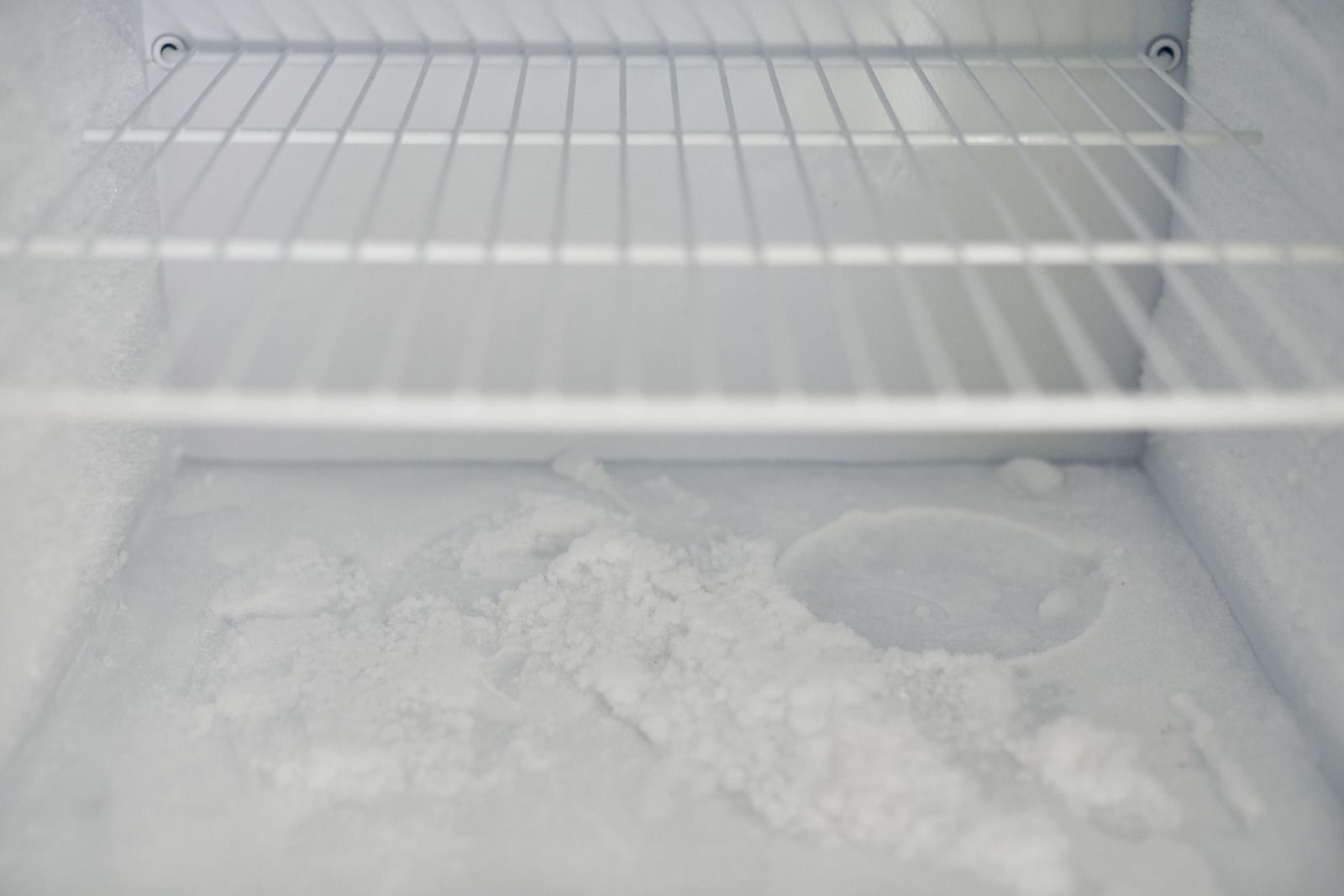 Empty frosted freezer shelf with ice buildup on the bottom.