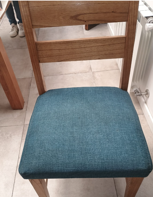 Silla tapizada azul en un comedor junto a una mesa de madera y un radiador.