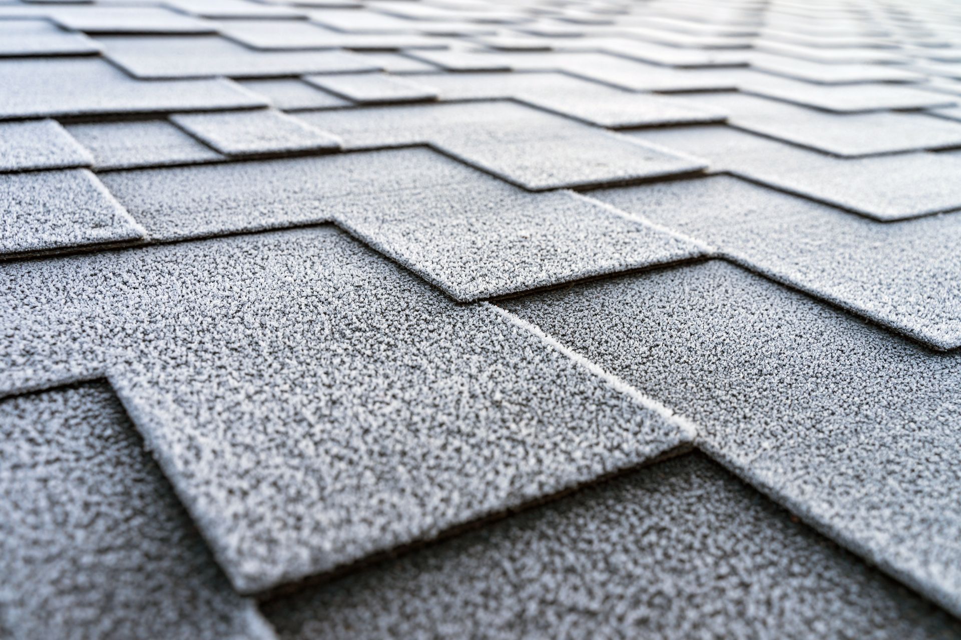 Close-up of gray asphalt roof shingles with a textured, overlapping pattern