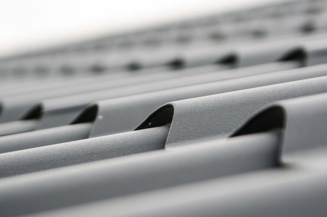 Close-up of gray metal roofing panels with repeating raised seams