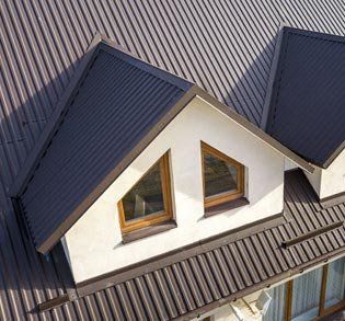 Aerial view of a house roof with two dark gables and brown-framed dormer windows.