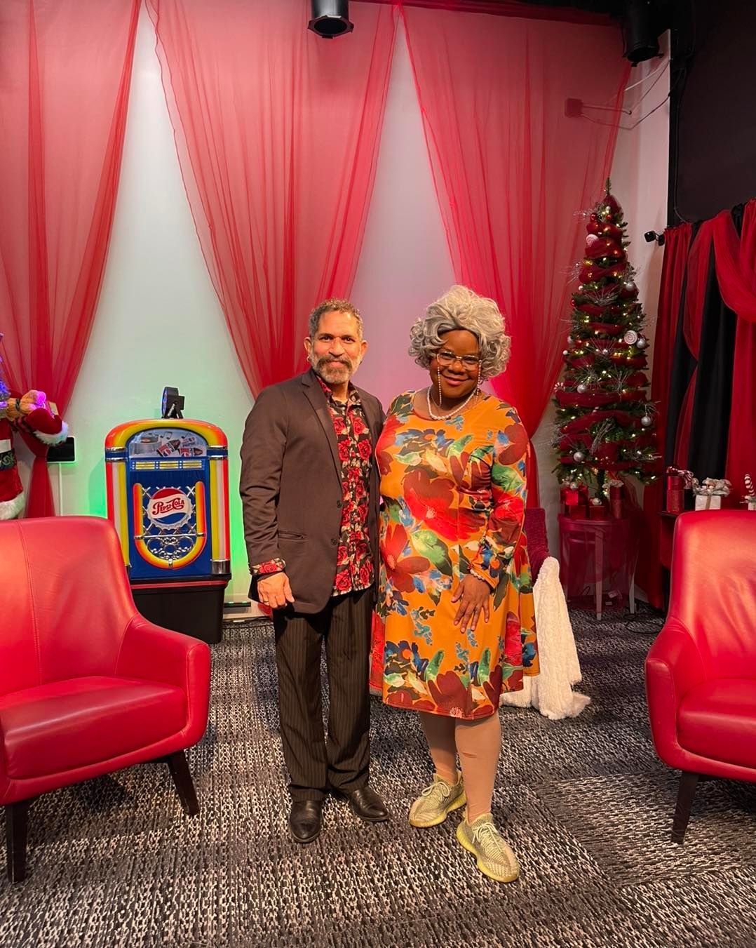 A man and a woman are standing next to each other in a room with a christmas tree.