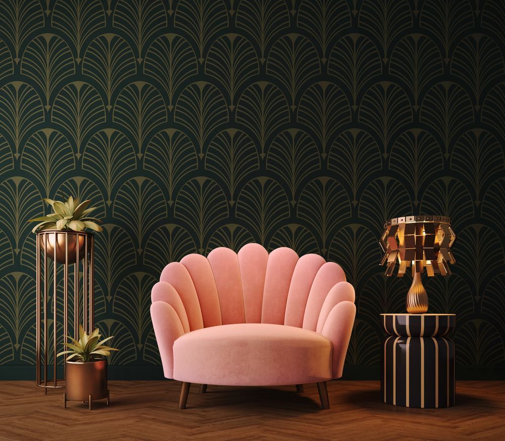 Poltrona rosa con schienale a conchiglia al centro di una stanza in stile art déco dai toni scuri, con carta da parati verde a motivi geometrici e dettagli dorati.