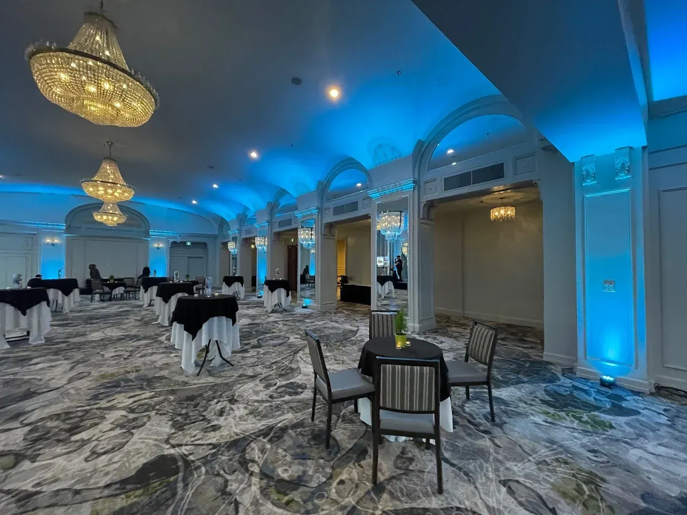 A large room with tables and chairs and blue lights on the ceiling.