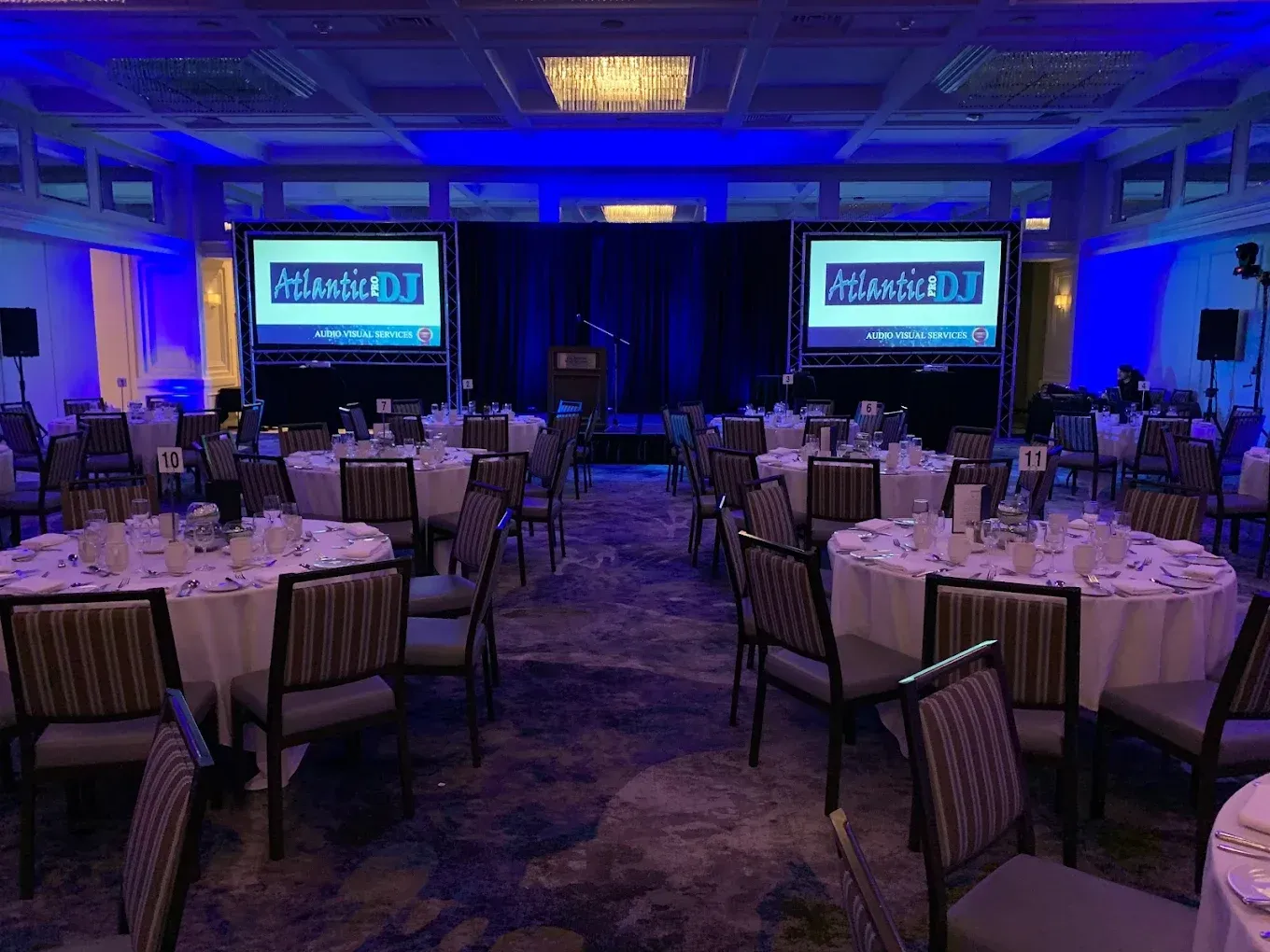 A large room filled with tables and chairs and two large screens.