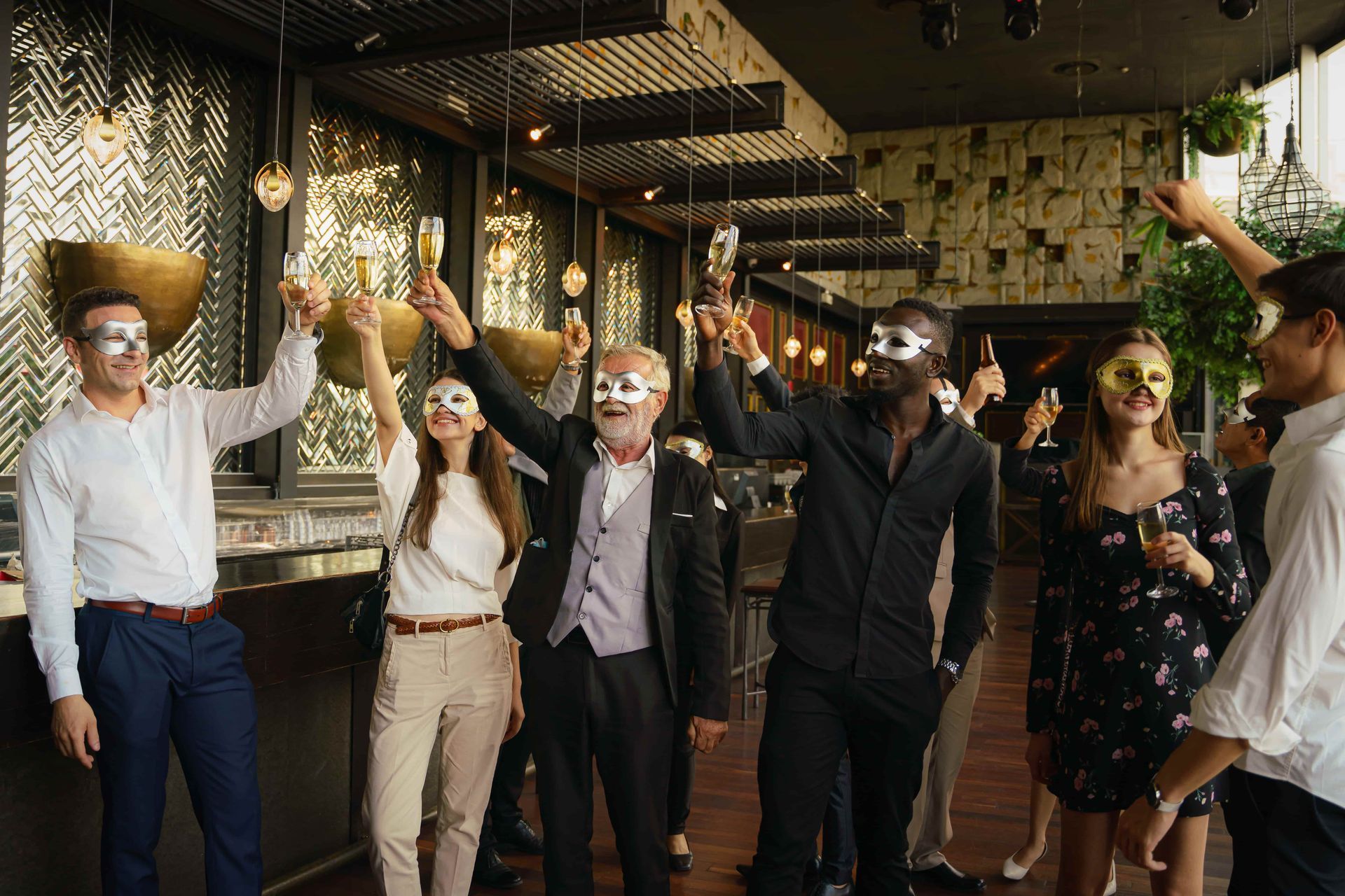 A group of people wearing masks are toasting with champagne.