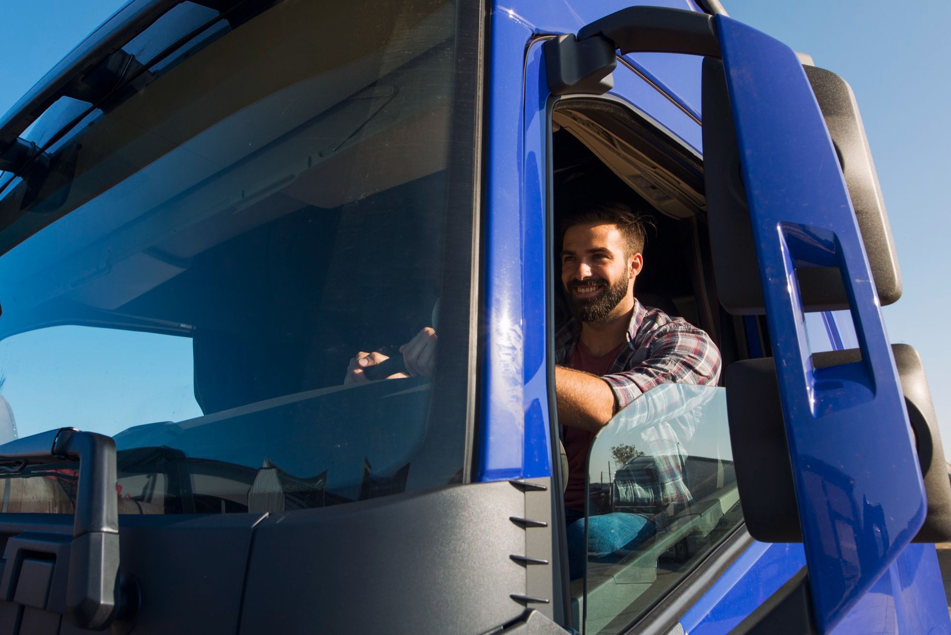Man driving a blue truck, looking out the open cab window