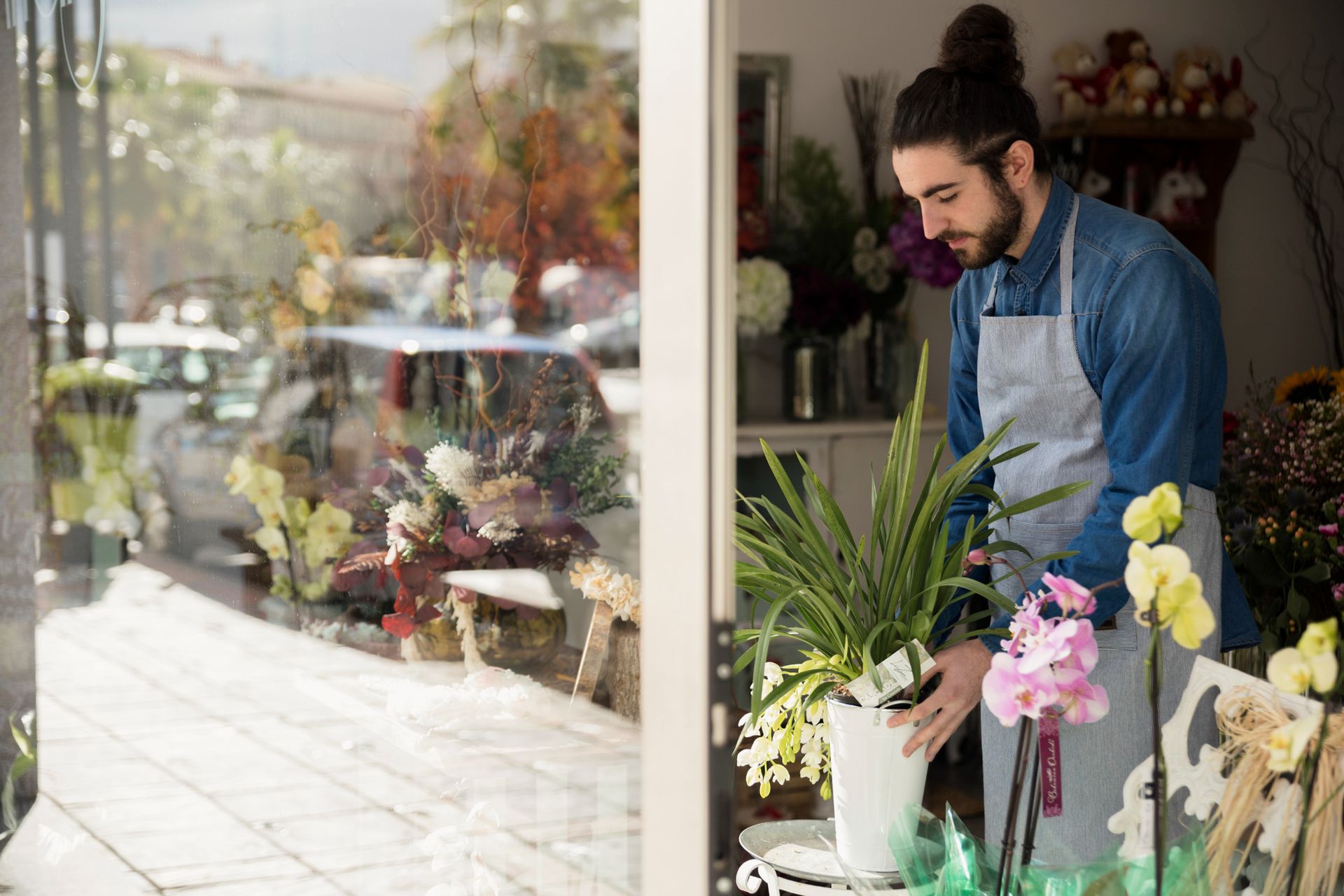 Florist arranging colorful flowers by a sunny shop window