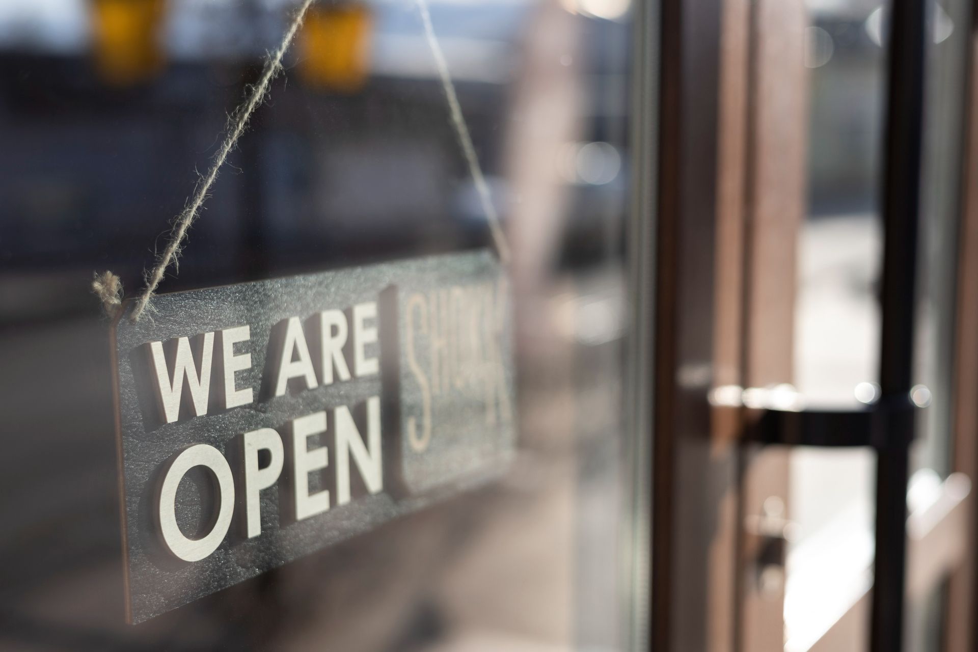 “We are open” sign hanging in a glass storefront window
