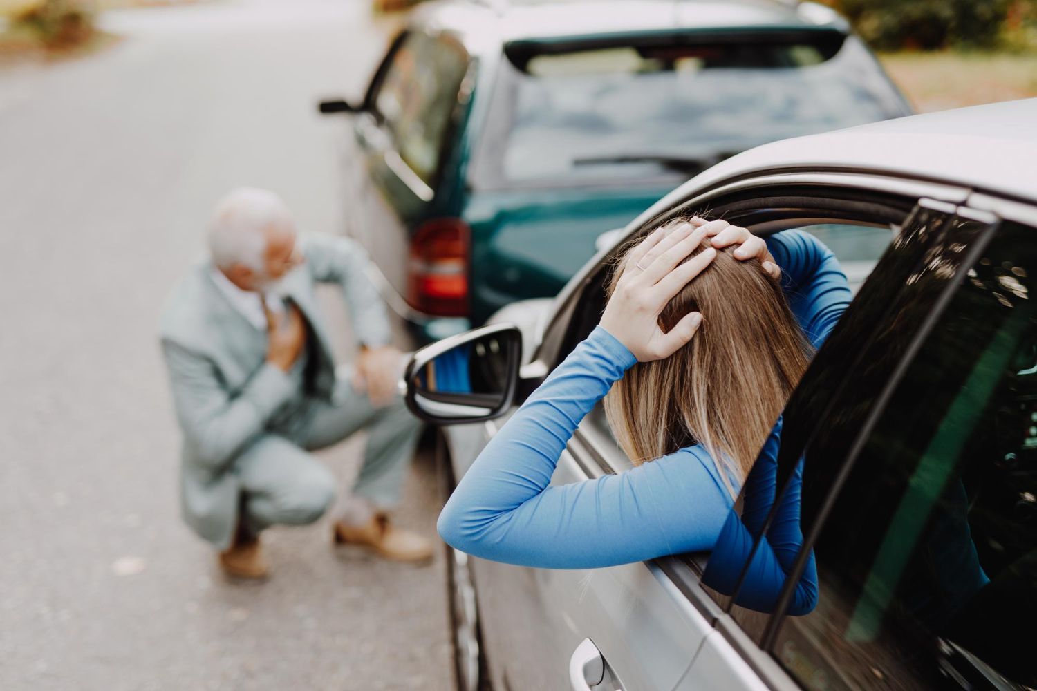 Woman covers her head while standing by a silver car after a rear-end collision; another person crouches nearby.