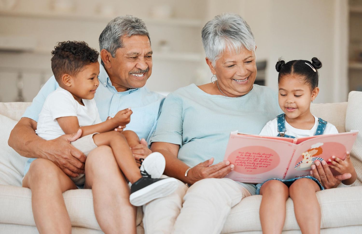 Family reading together on a couch, with two adults and two children sharing an open book