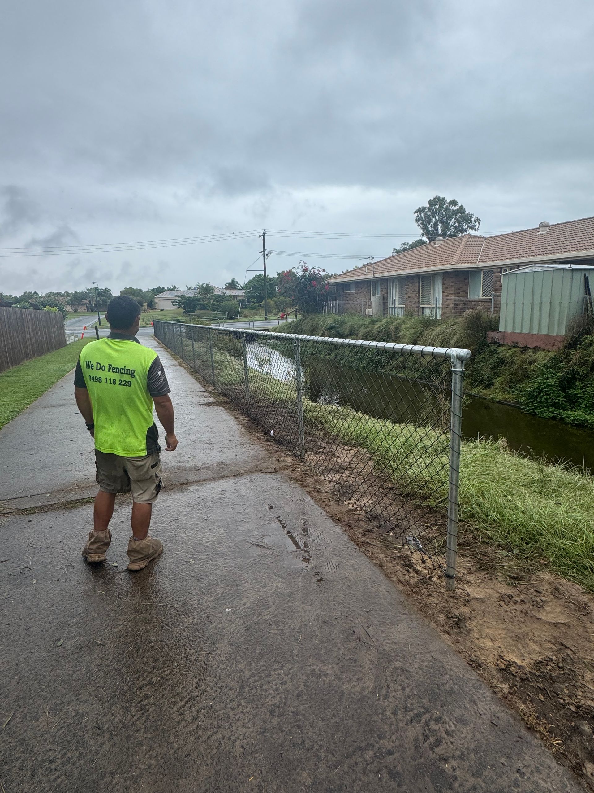 Man Looking At An Aluminium Chain Link  Fence — We Do Fencing in Sunshine Acres, QLD
