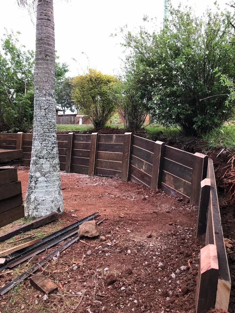 A Wooden Fence is Being Built in a Yard Next to a Palm Tree — We Do Fencing in Sunshine Acres, QLD