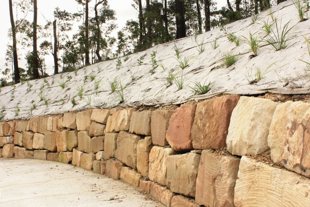 A Stone Wall is Surrounded by Trees and Grass on a Hillside — We Do Fencing in Sunshine Acres, QLD