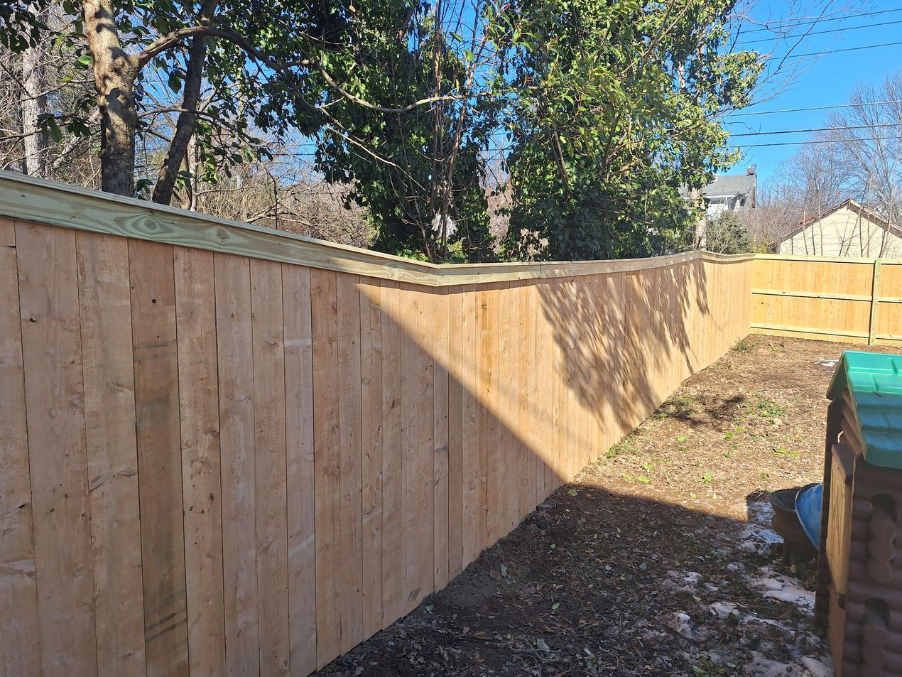 A Wooden Fence in A Backyard with Trees in The Background.