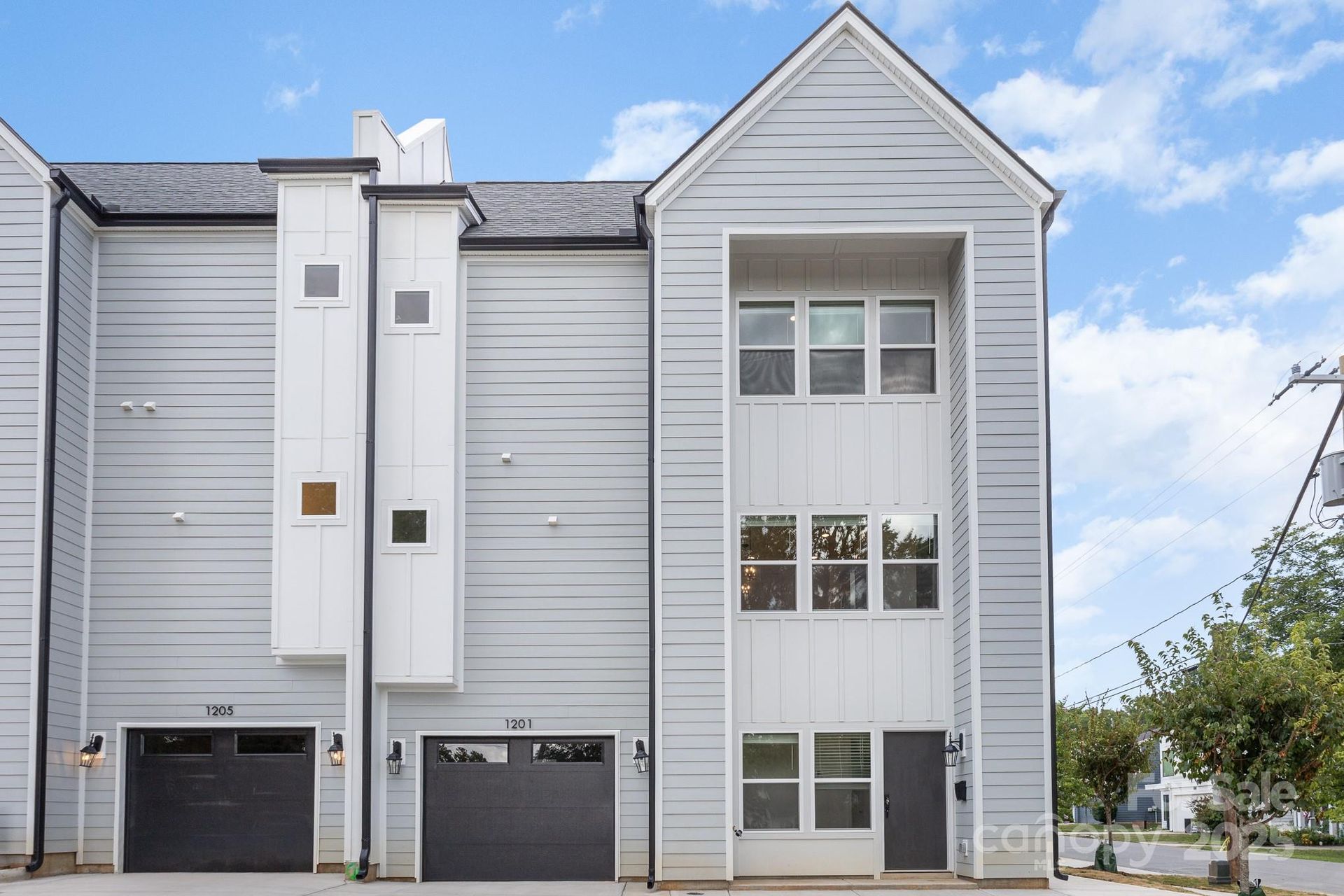 A white house with a black garage door is for sale.