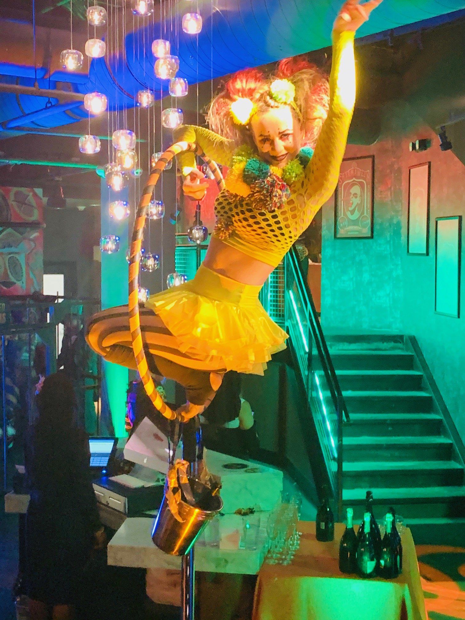 A woman in a yellow dress is hanging from a hoop in a room.