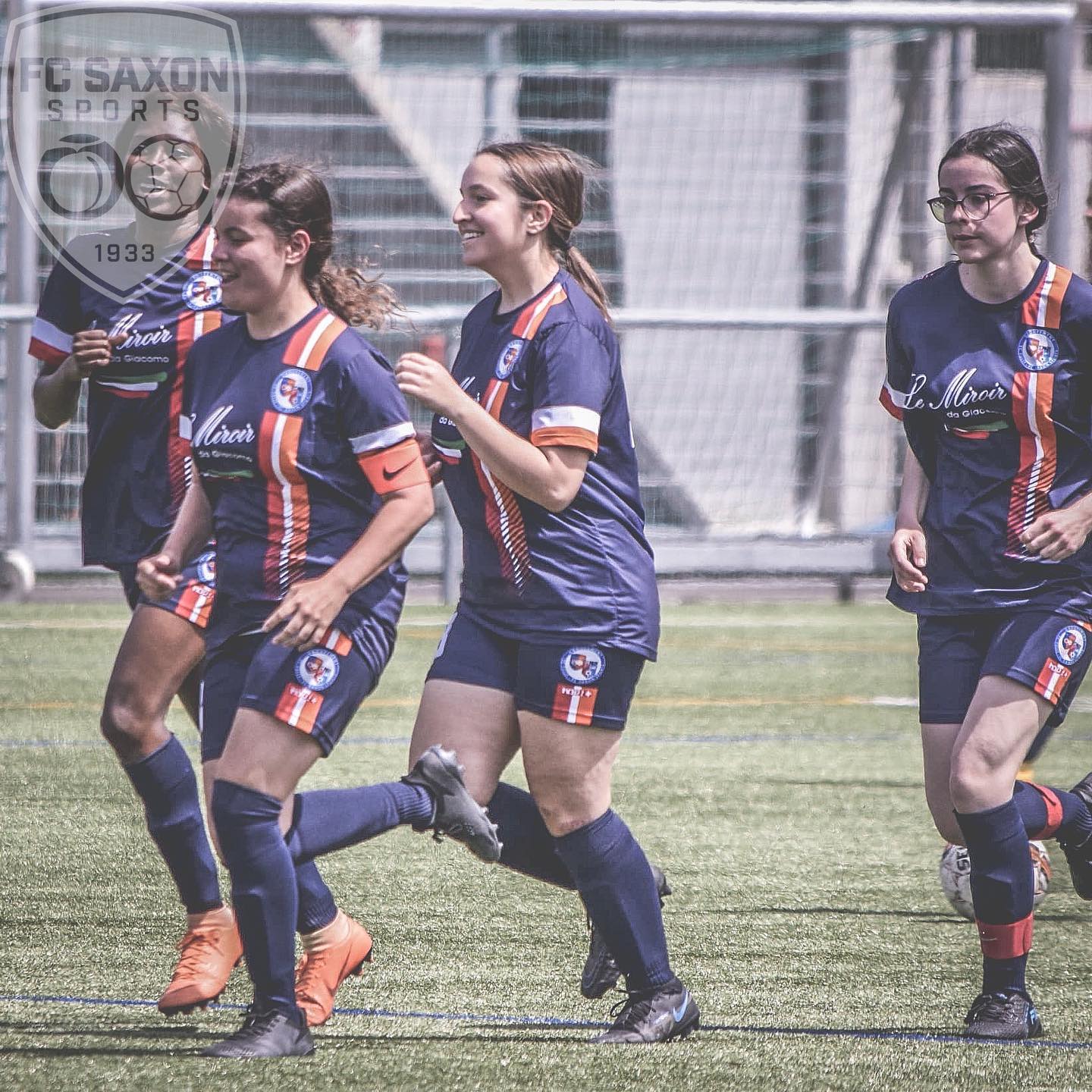 Un groupe de joueuses de football courent sur un terrain.