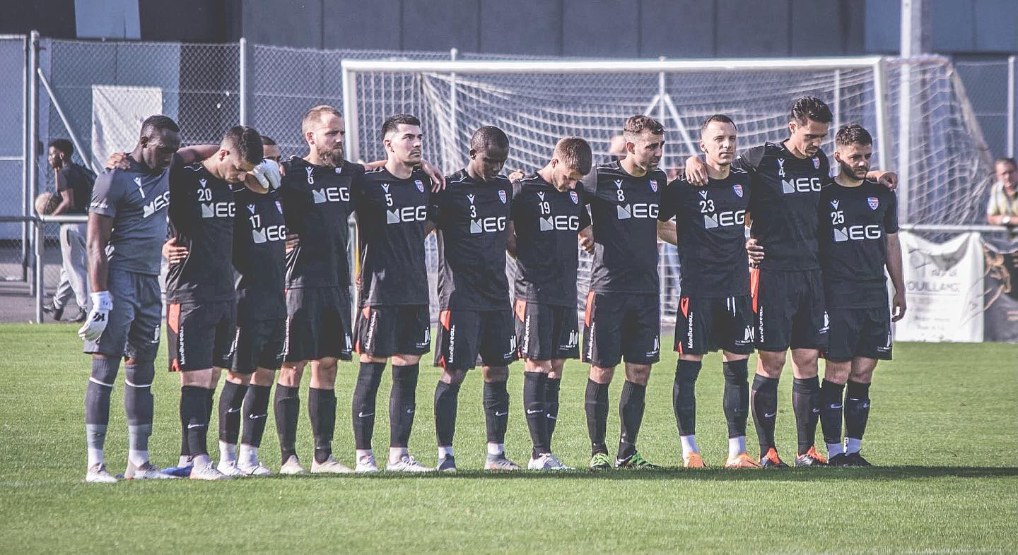 Un groupe de joueurs de football se tient regroupé sur un terrain.
