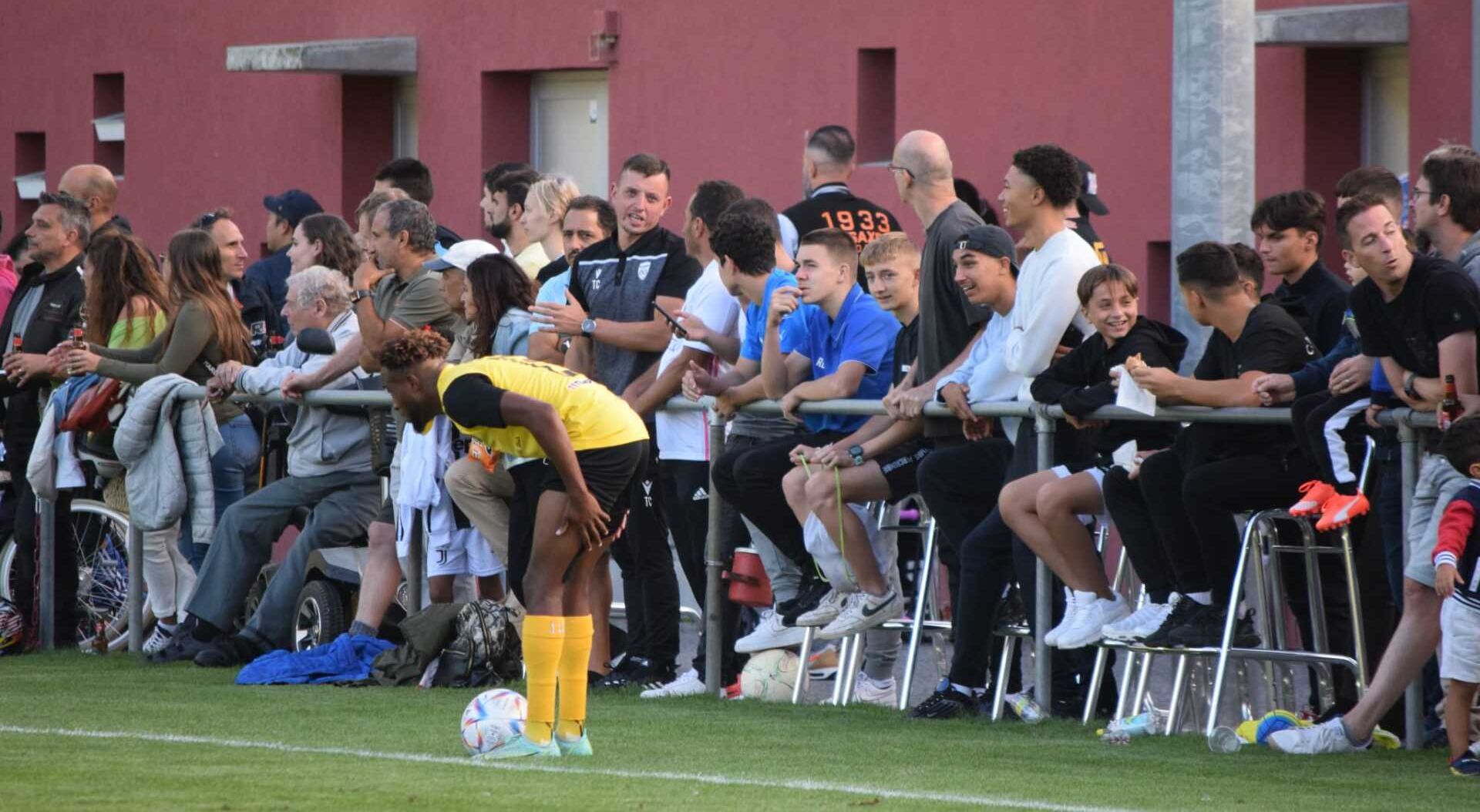 Un groupe de personnes regarde un match de football sur un terrain.