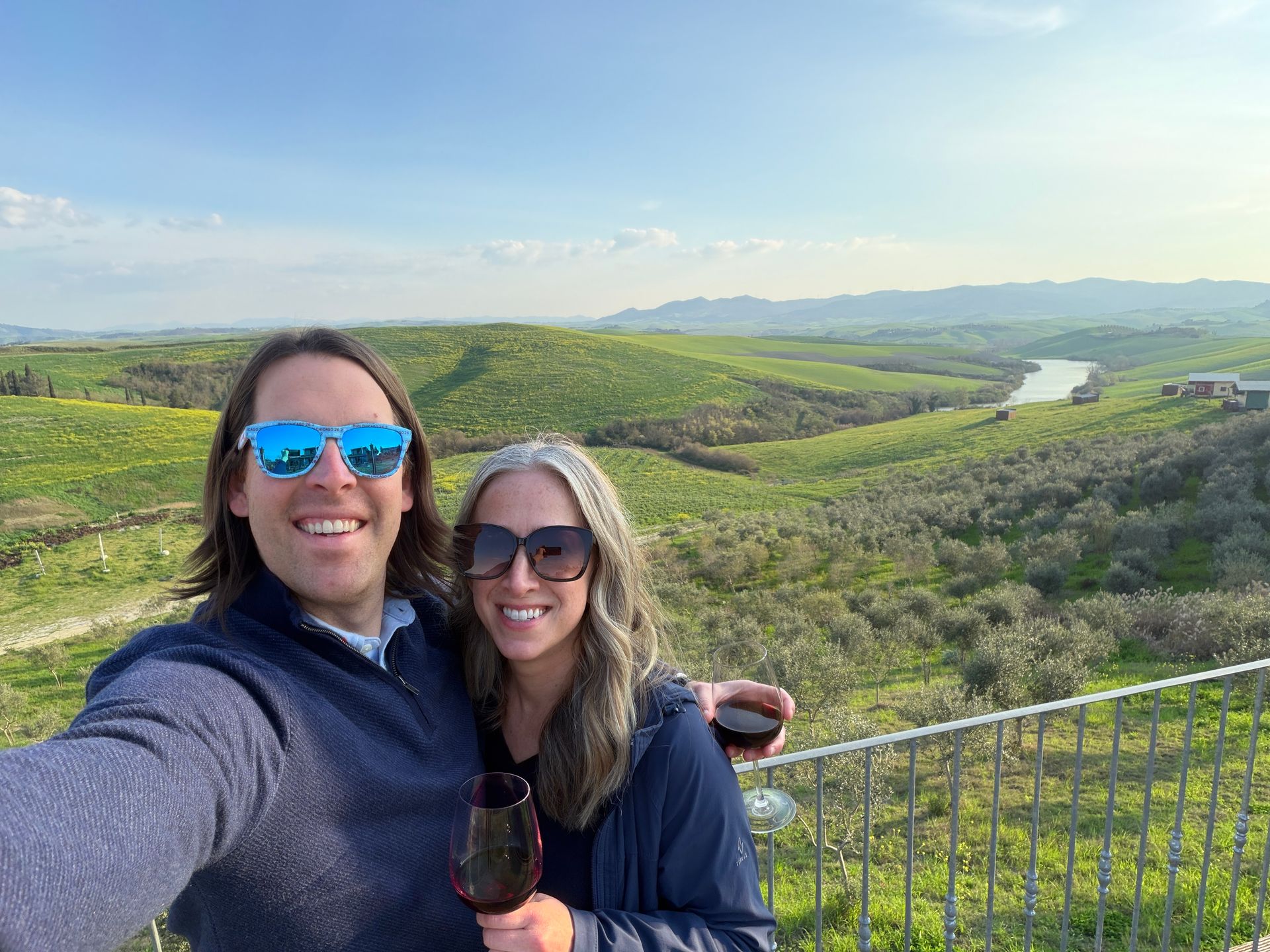 Brian Voss and family smiling with wine on a scenic hillside overlooking a green valley and river