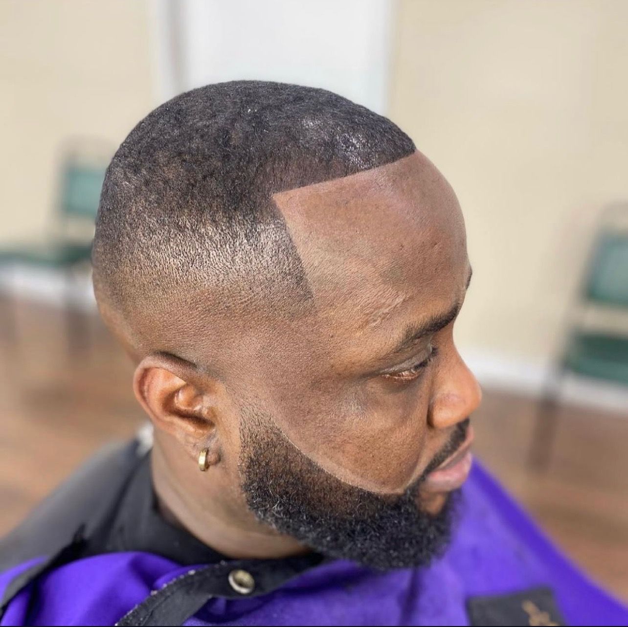 A man with a beard is getting his hair cut at a barber shop.