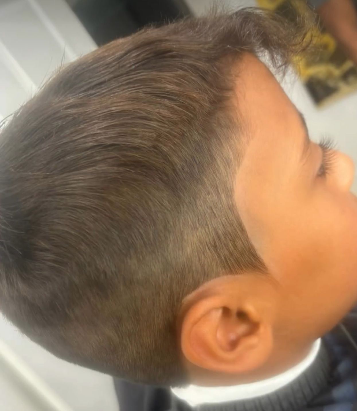 A young boy is getting his hair cut at a barber shop.