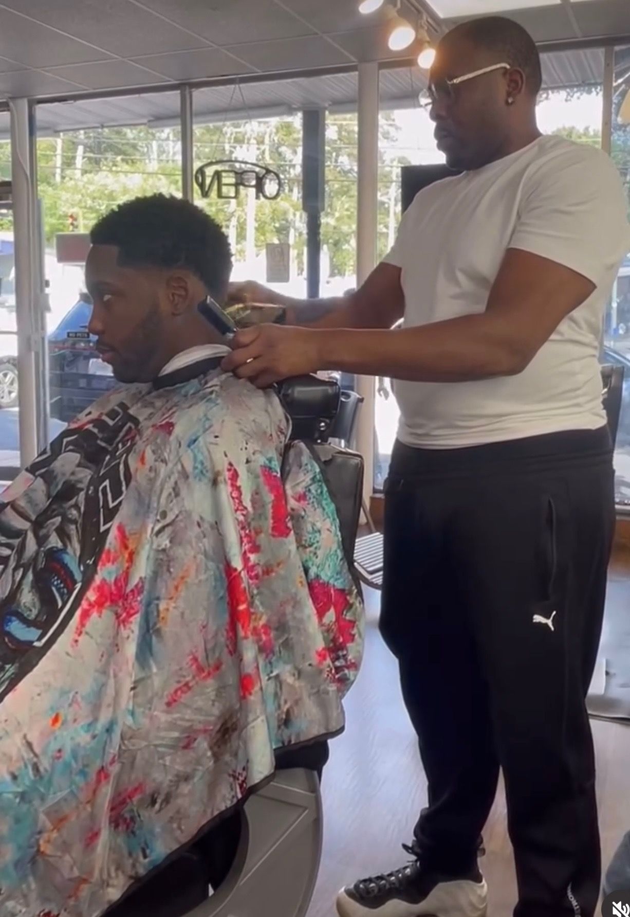 A man is getting his hair cut by a barber in a barber shop.