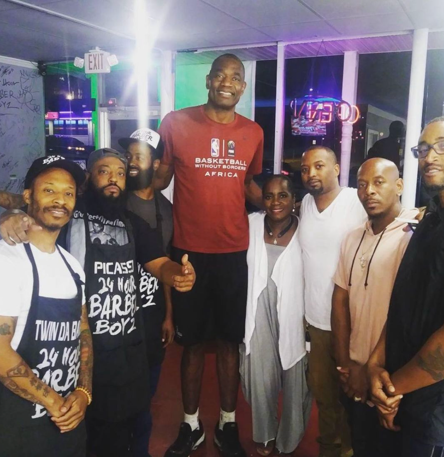 A group of people posing for a picture with one man wearing a shirt that says picare 24 no bar 2 boys