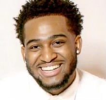 A man with a beard is smiling and wearing a white shirt and tie.