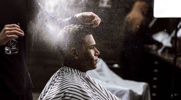 A man is getting his hair cut at a barber shop.