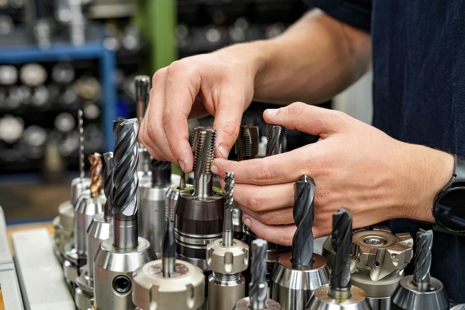 Person selecting a cutting tool from a display. Hands are prominent. Tools are in a metal holder.
