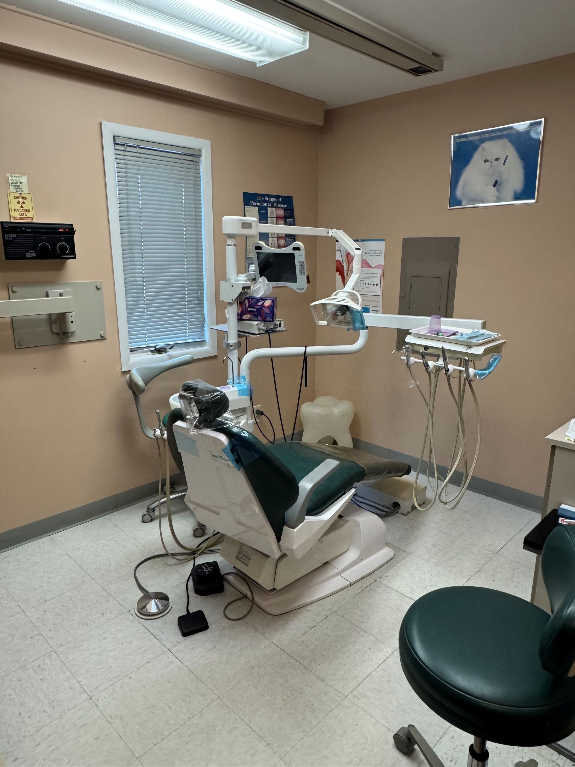 Dental exam room with chair, overhead light, instruments, and sink cabinets