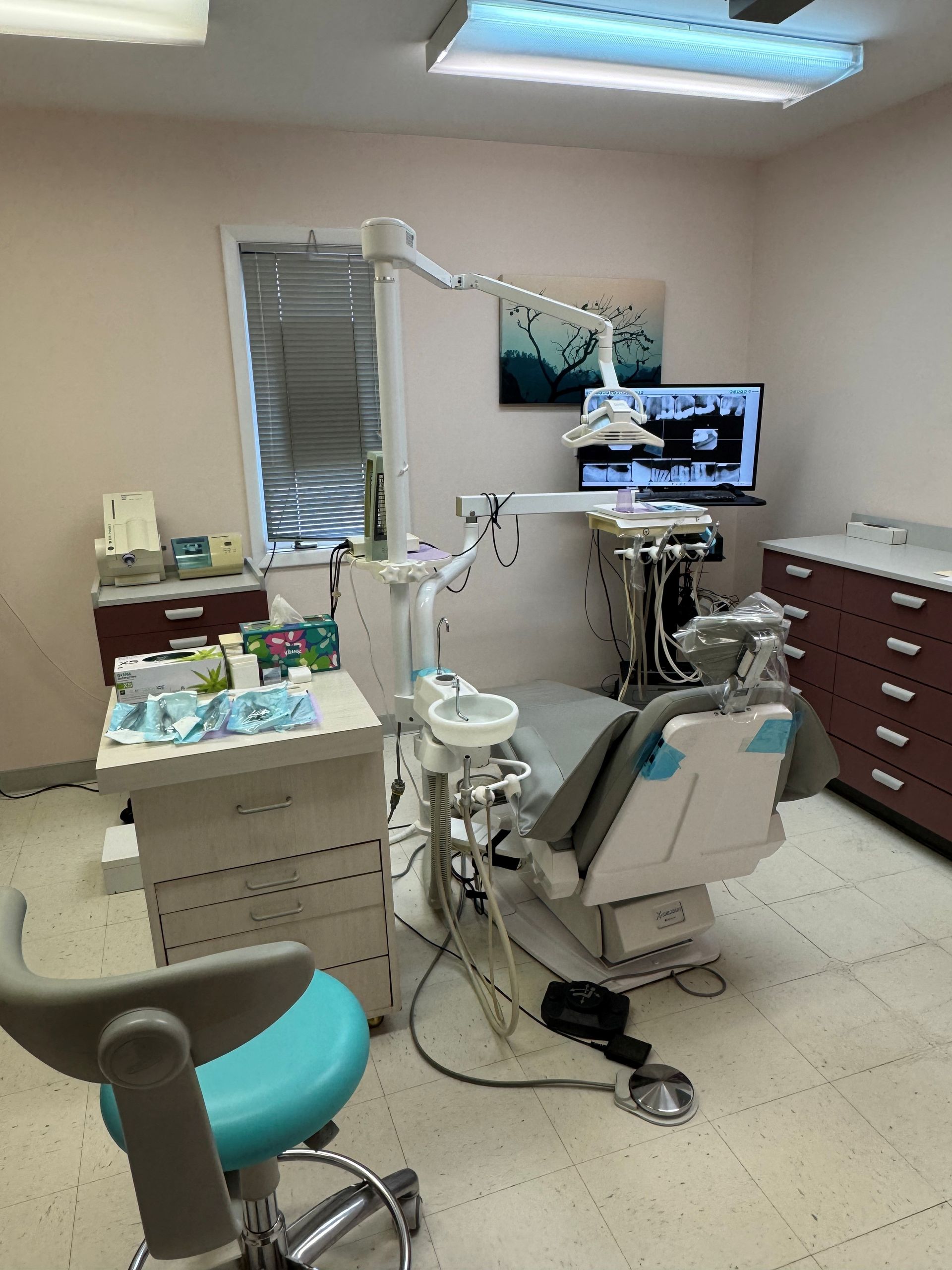 Dental exam room with chair, monitor, and cabinets in a clinical setting