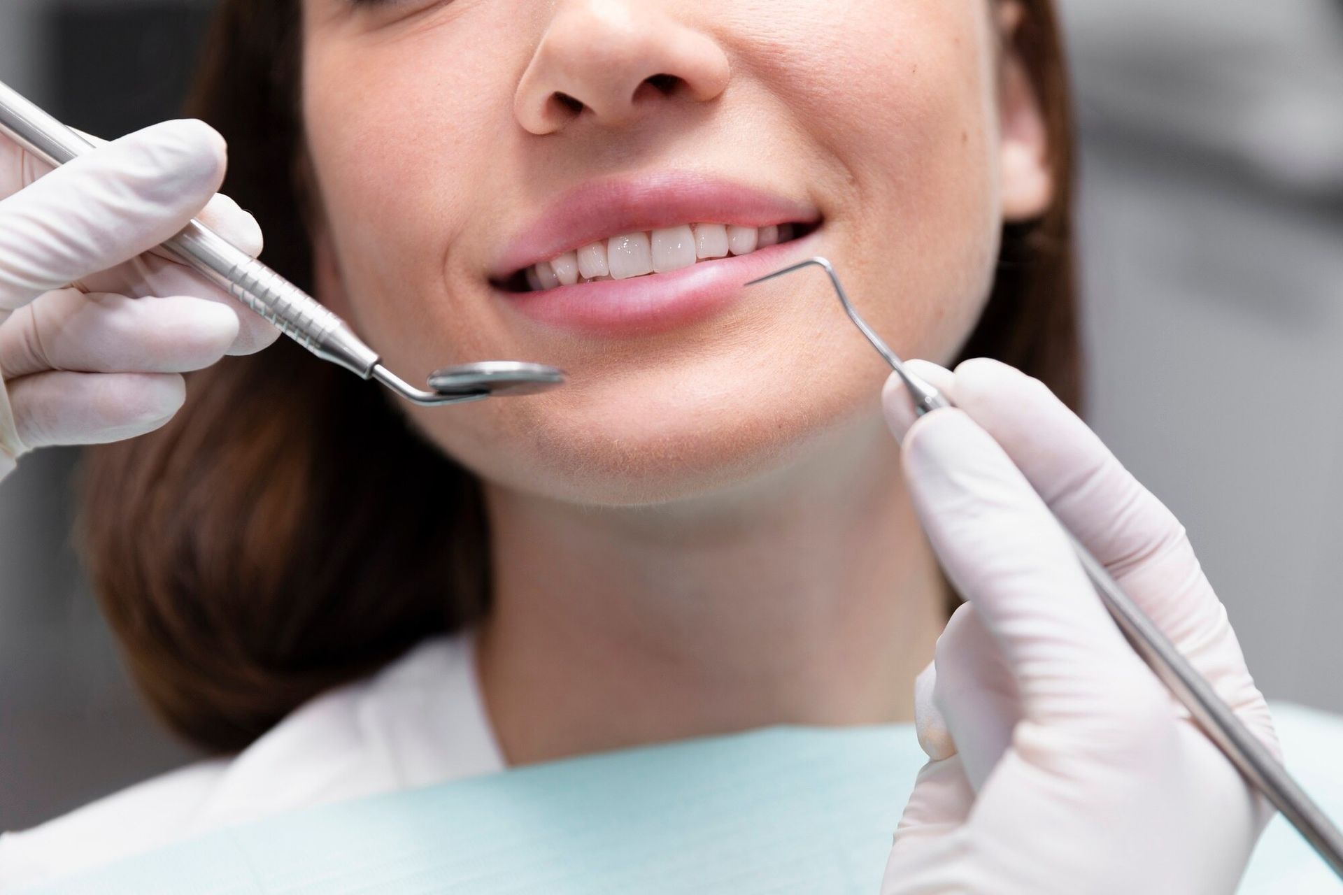 Dental tools examining a smiling patient’s teeth and mouth