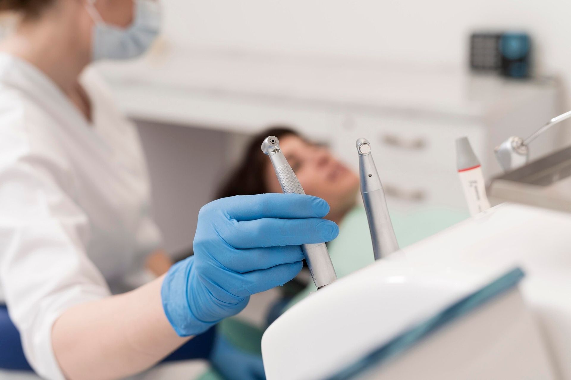 Gloved hands holding dental tools beside a patient in a dental clinic