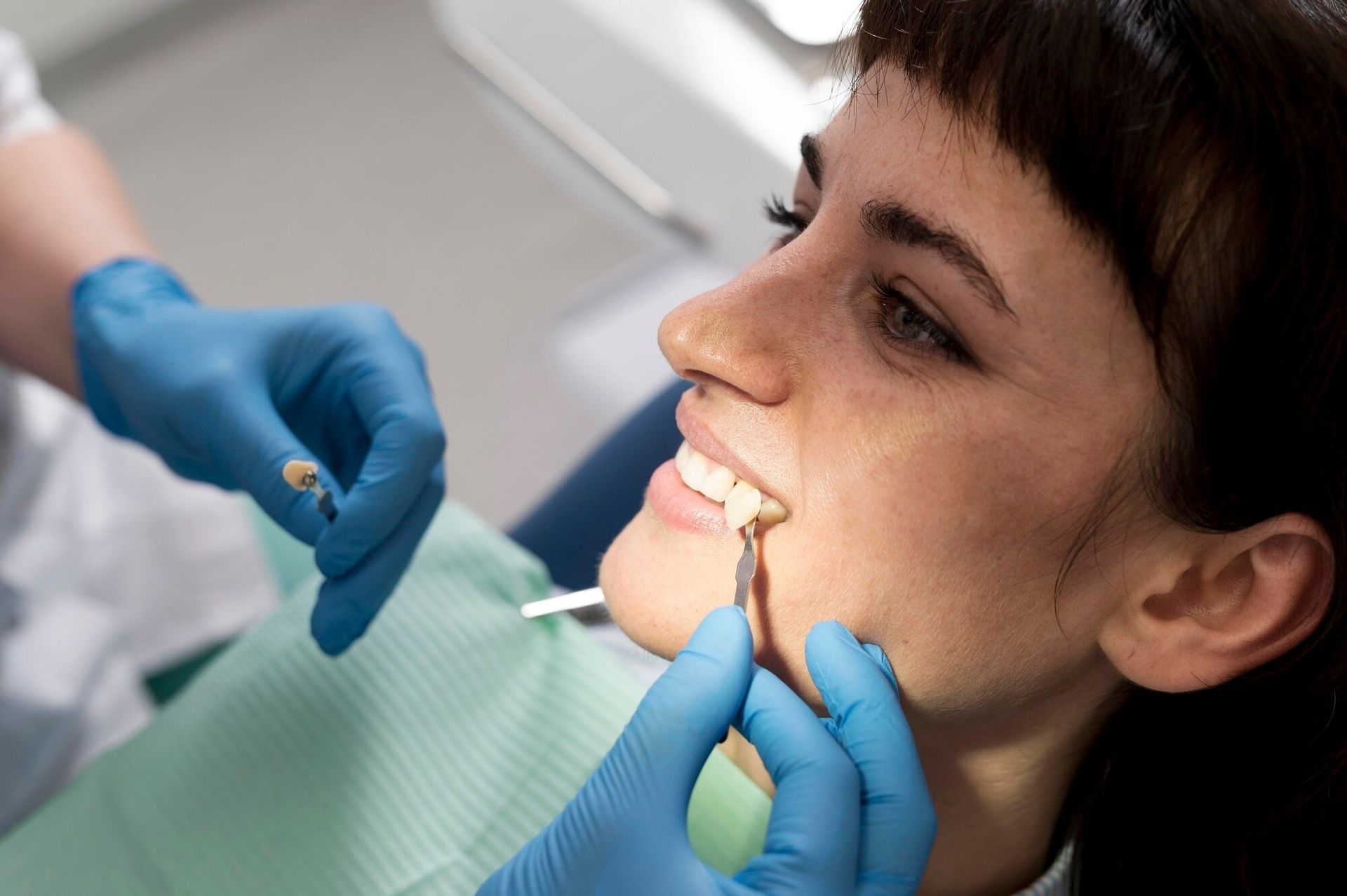 Dentist examining a patient’s mouth with blue gloves and dental tools