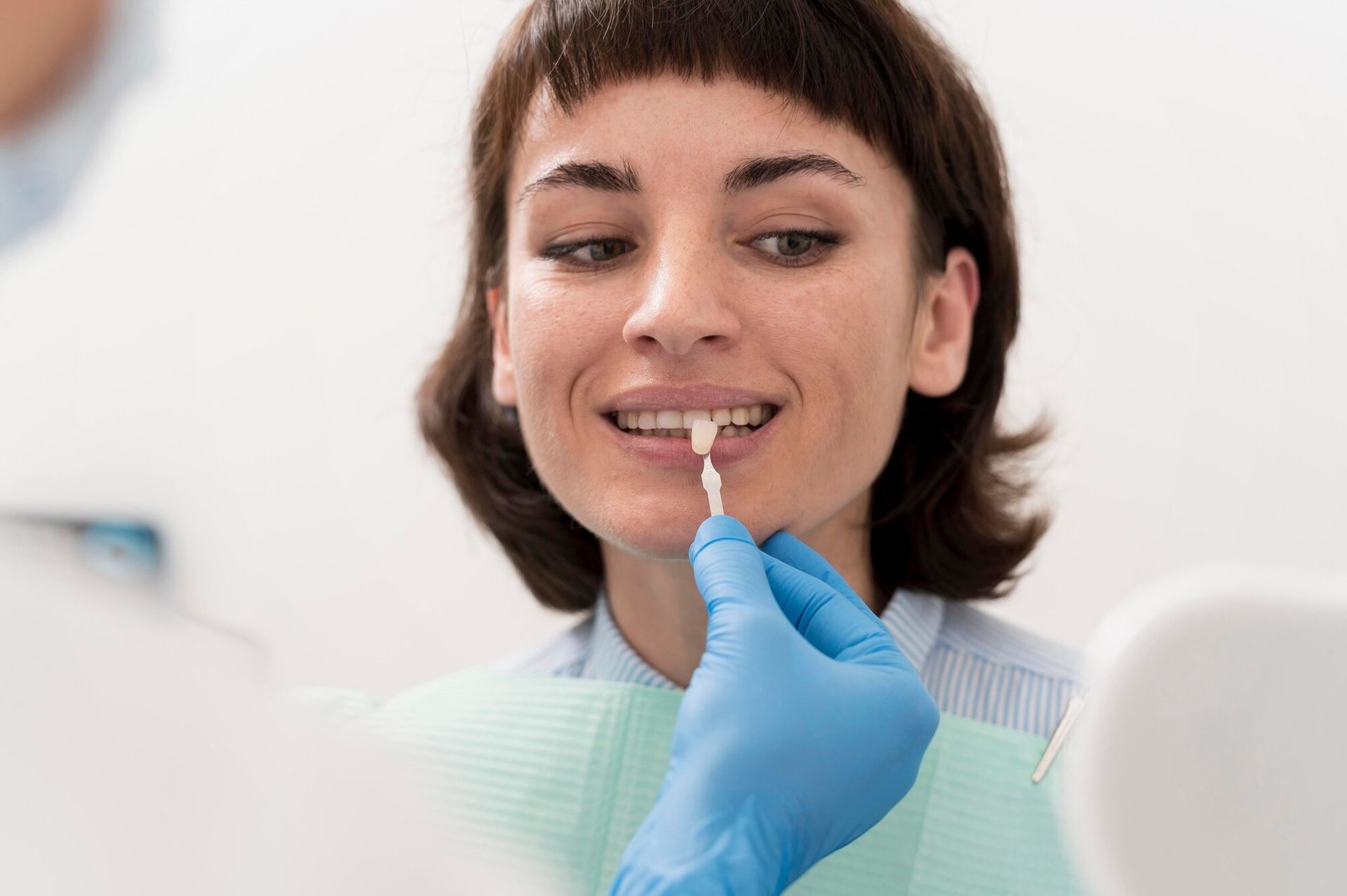 Dental checkup with a woman smiling as a gloved hand examines her teeth