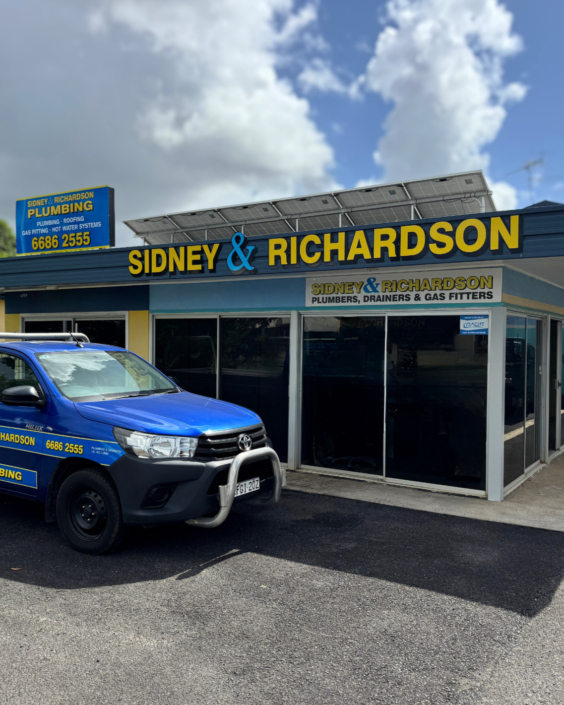 Blue pickup truck parked outside Sidney & Richardson storefront under a cloudy sky