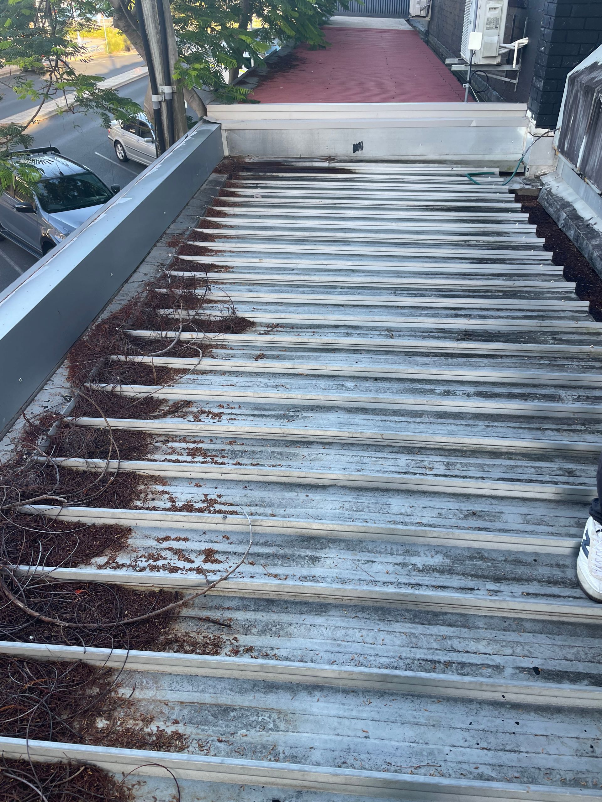 Weathered corrugated metal rooftop with rust spots and a white parapet wall at the top