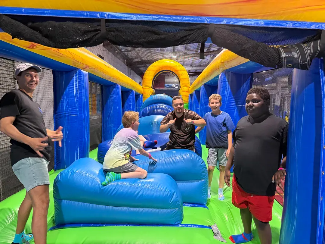 People posing in a blue and green inflatable obstacle course indoors