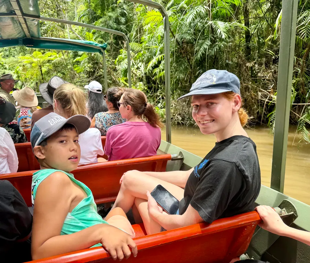 Two people sitting in a red ride vehicle on a jungle tour, smiling at the camera.