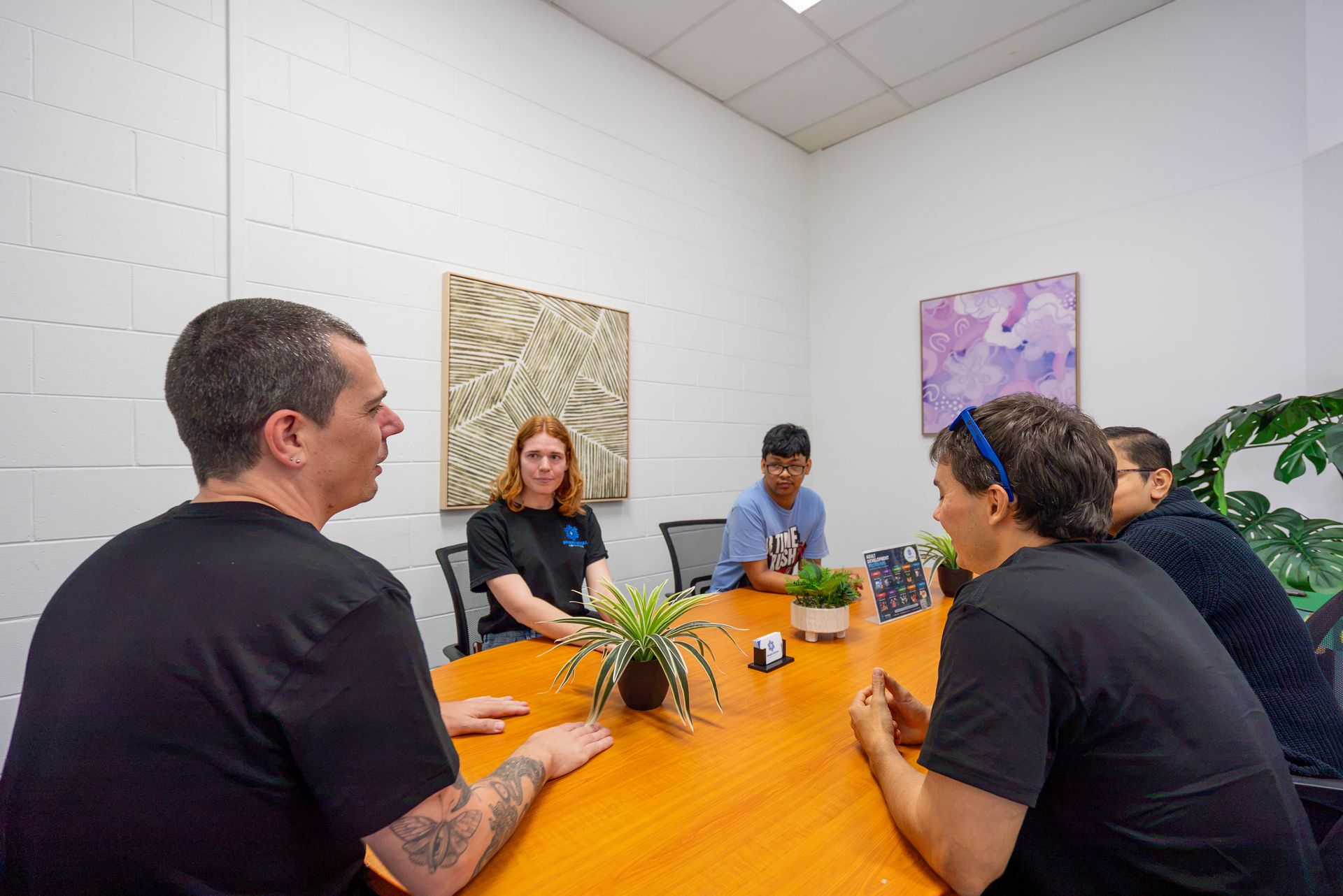 Four People Seated Around an Orange Conference Table — Sparks Social Abilities in Bungalow, QLD